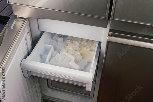 Fotografia Ice cubes in the tray inside of automatic ice maker in a modern refrigerator