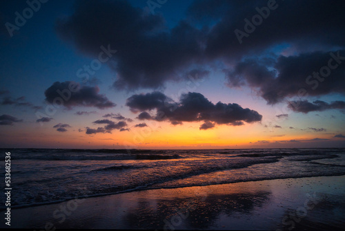 Beautiful sunset sunrise at the beach with dramatic clouds in the blue purple yellow sky over the sea - Bali