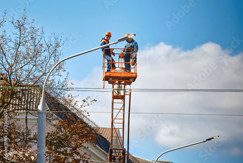 Quadro em tela Workers on lifting platform installing new LED lamps