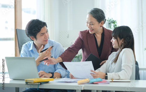 Friendly middle aged female leader having a discussion, planning new strategy with young businesspeople in office.