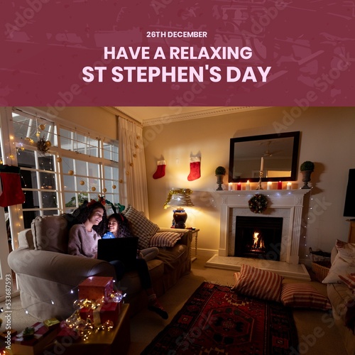 Composition of st stephen's day text and biracial mother and daughter at christmas by fireplace photo
