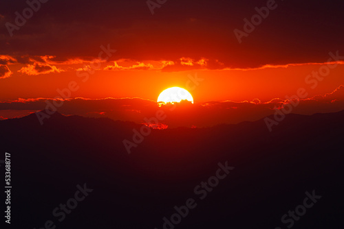 Red light from sunset behind cloudy sky.