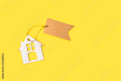 Casita de madera blanca con una etiqueta en blanco sobre un fondo amarillo brillante liso y aislado. Vista superior y de cerca. Copy space photo