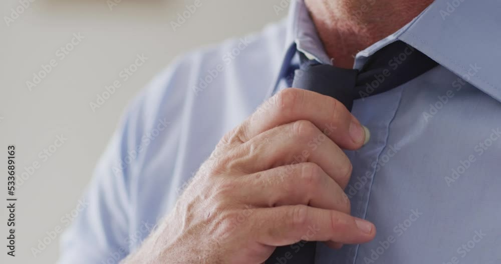 Happy caucasian man standing in living room and wearing tie