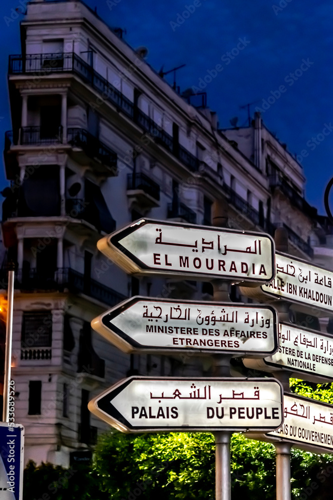 Algiers by night. Direction signalisation panels in French and Arabic language of El Mouradia, Ministry of Foreign Affairs and People's Palace.  Ibn Khaldoun, Ministry of defense and Government Palace