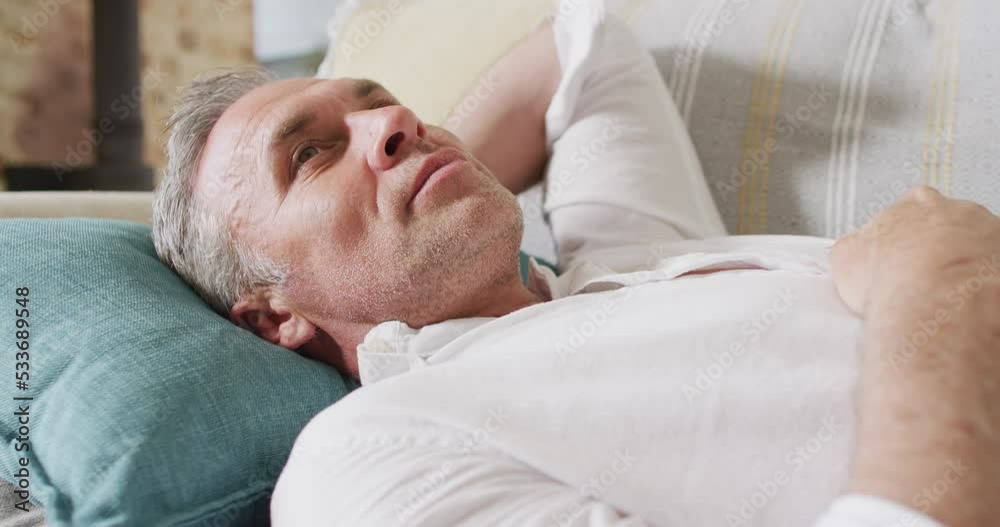 Happy caucasian man lying on sofa in living room and smiling Happy caucasian man lying on sofa in living room and smiling