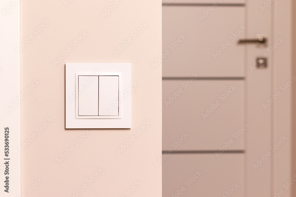White electrical switch on beige wall next to the door in modern apartment White electrical switch on beige wall next to the door in modern apartment