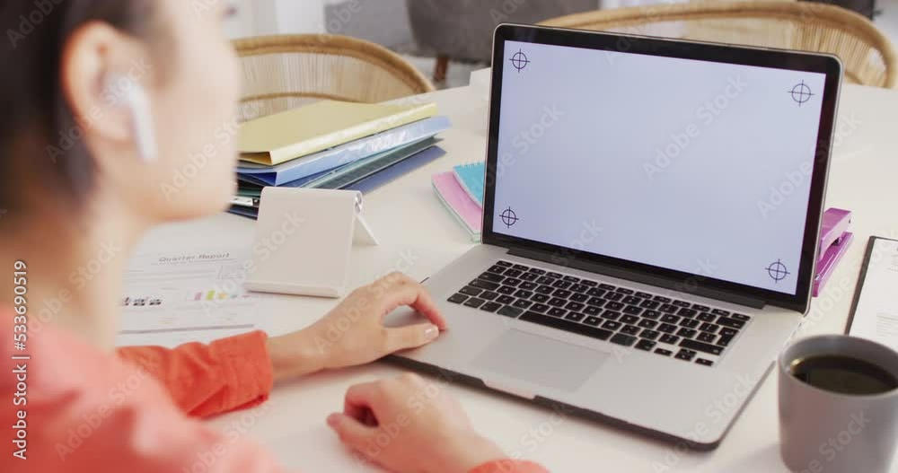 Biracial woman sitting at table and working with laptop with copy space Biracial woman sitting at table and working with laptop with copy space