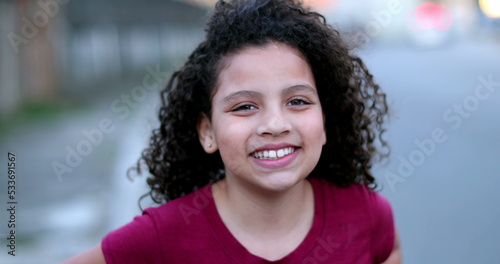 Little child girl smiling at camera. Hispanic female kid portrait face close-up