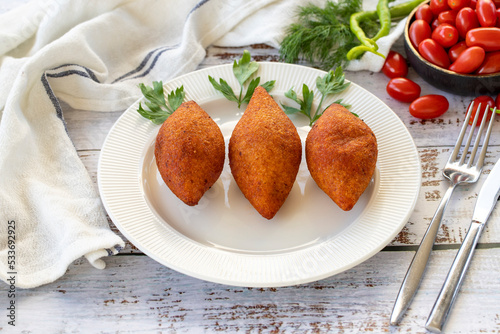 Stuffed meatballs. Turkish cuisine delicacies. Kibbeh or icli kofte on wood floor. close up photo