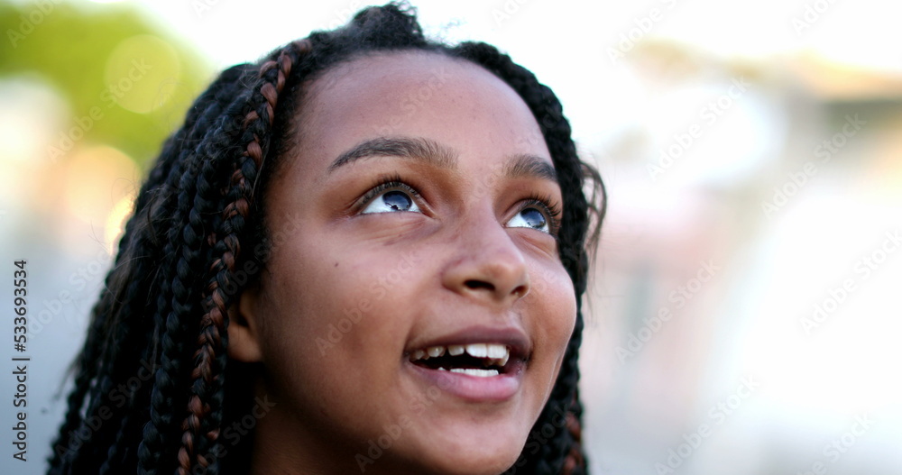 Happy black preteen girl child face smiling and looking up to sky Happy black preteen girl child face smiling and looking up to sky