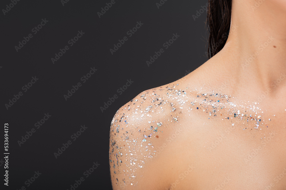 cropped view of young woman with sparkling glitter on clavicle and bare shoulder isolated on grey.