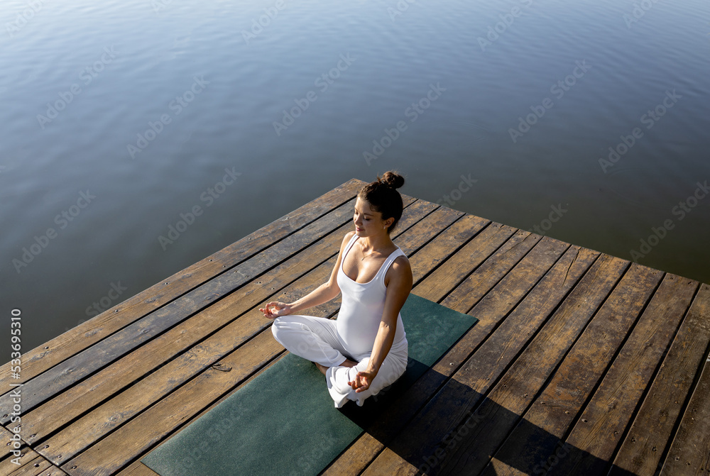 Pregnant woman doing yoga at lake during the day. Pregnant woman doing yoga at lake during the day.