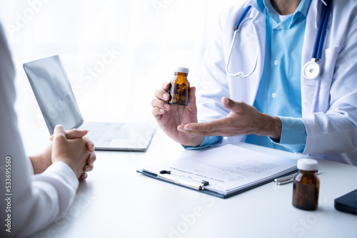 Doctor and patient sitting and talking at medical examination at hospital office  close-up. Therapist filling up medication history records. Medicine and healthcare concept.