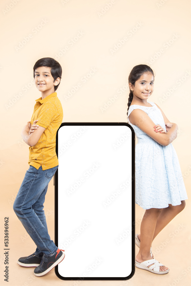 Happy LittleIndian Kids Standing With Big Huge Blank Smartphone Screen, Mobile Cell Phone Copy Space For Your App Or Website Design, Isolated On Plane Studio Background, Online Shopping, Mockup, Happy LittleIndian Kids Standing With Big Huge Blank Smartphone Screen, Mobile Cell Phone Copy Space For Your App Or Website Design, Isolated On Plane Studio Background, Online Shopping, Mockup,