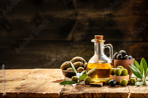 Olive oil in bottles with black and green olives and leaves. extra virgin olive oil jars on a wooden background. place for text