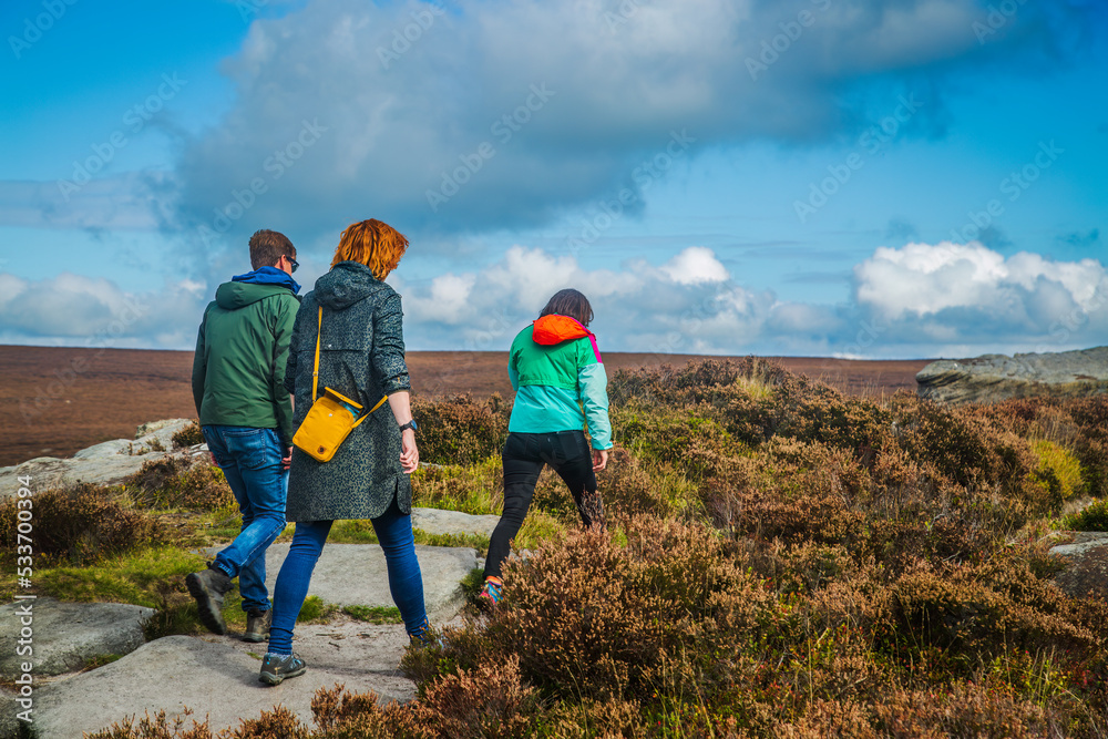 Three female hill walkers heading along Burbage edge in the peak District of the Derbyshire dales