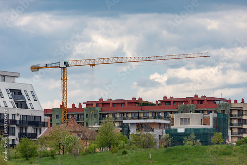 Urban development with a construction crane on a site among apartment buildings on a cloudy day in a residential neighborhood