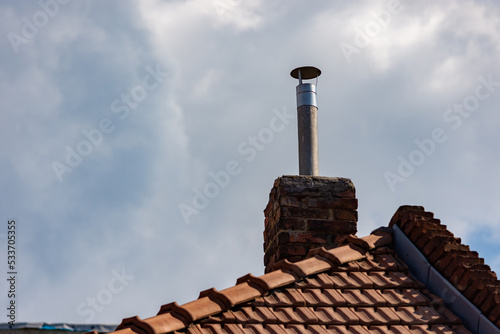 Vintage chimney made of bricks with a conic cowl head pipe on top