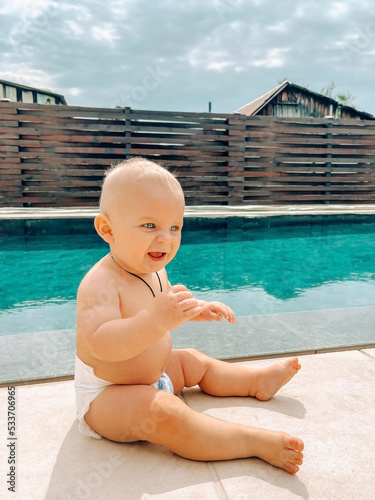 Cute baby boy spending time near the swimming pool