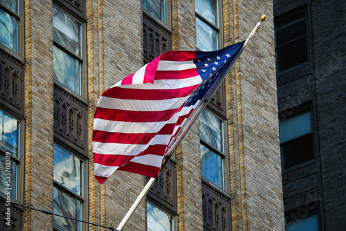 National flag of the United States of America winding in the balcony of an old skyscraper concrete brick building from New York