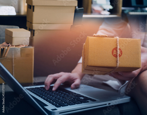 Startup SME small business entrepreneur of freelance Asian woman using a laptop with box Cheerful success Asian woman her hand lifts up online marketing packaging box and delivery SME idea concept © ARMMY PICCA