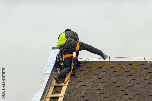 Repairman climbs a ladder while repairing the roof