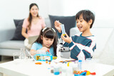Kid playing a microscope for scientific experiments at home.Young beautiful teacher and toddlers playing on the floor with lots of toys at kindergarten