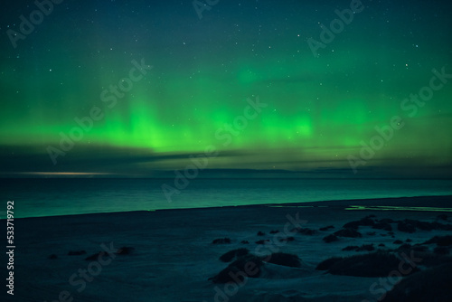 Green Northern Lights dancing over beach. High quality photo