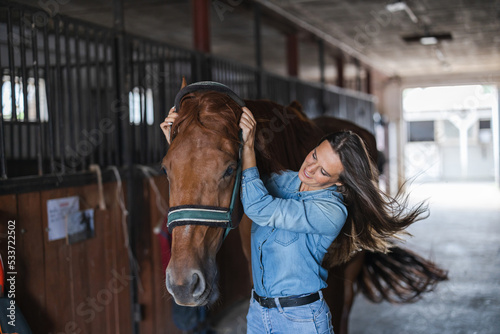 Woman taking care of her horse in stable 