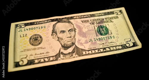 Closeup shot of a five dollar bill on a black surface photo