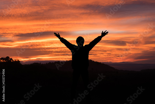 man raising his arms and light in the morning