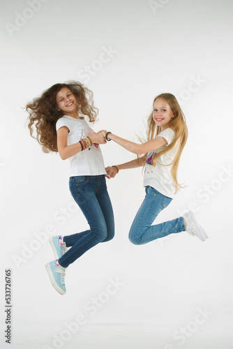 Two teenage girls on a pure white background in a jump. Emotions of joy