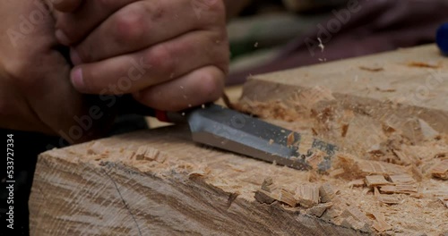 Close up detail of carpenter chiseling a wooden beam for log cabin construction in the mountains photo