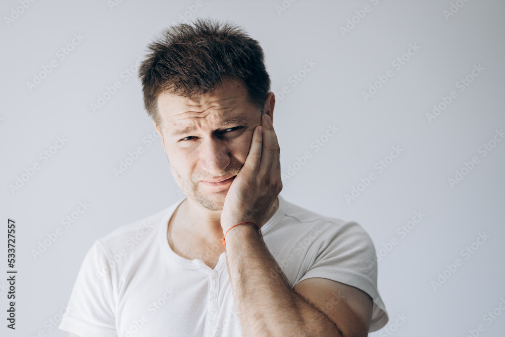 Stress at work. Toothache in man. Guy holds his hand to his face from