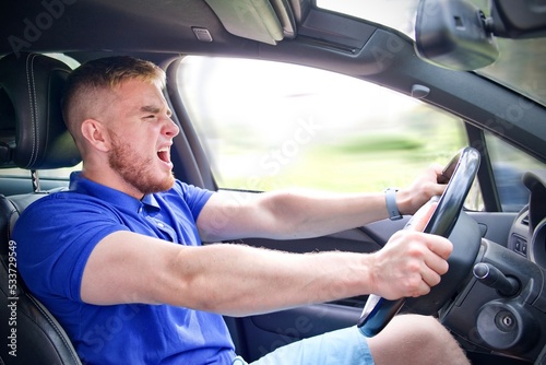 Tableau sur toile Handsome frightened fearful guy, driver, young scared man shocked about to have accident, driving car fast on road holding steering wheel of automobile