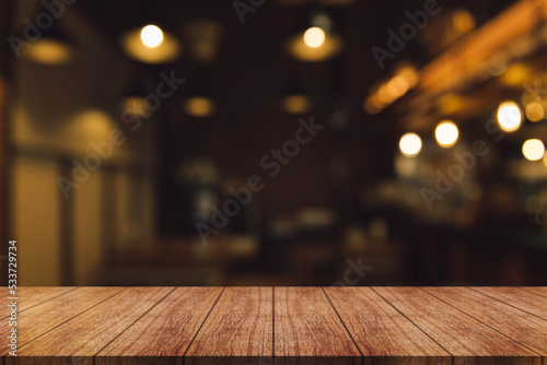  Empty wooden table top with lights bokeh on blur restaurant background.