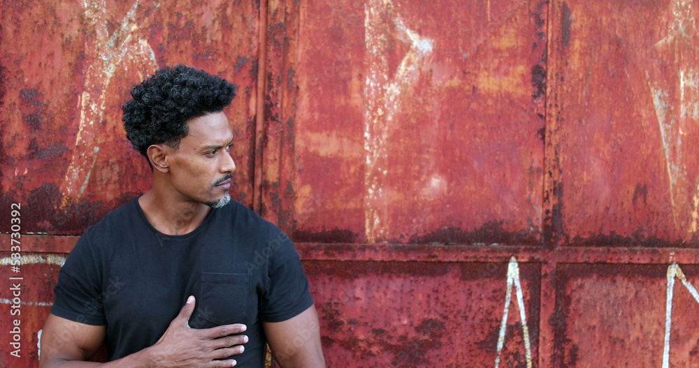 Serious African man standing outside surveilling neighborhood street ...