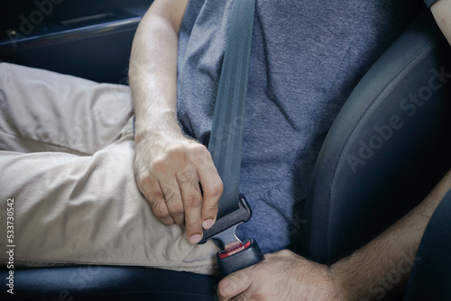 Close-up of a man s hand fastening a car s seat belt before driving. male driver fastens his seatbelt of the car for safety before the trip.