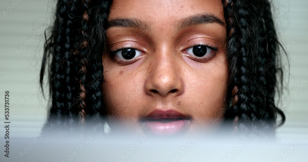 Portrait hispanic black girl looking at computer screen face closeup Portrait hispanic black girl looking at computer screen face closeup