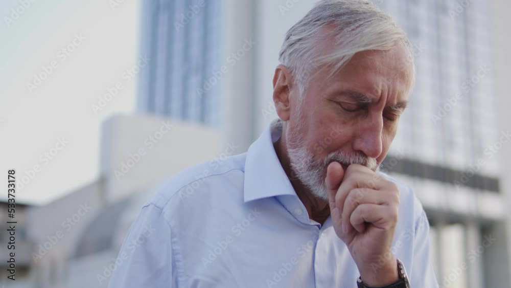 Unhealthy gray-haired man coughing, closing mouth with fist, covid-19 infection Unhealthy gray-haired man coughing, closing mouth with fist, covid-19 infection