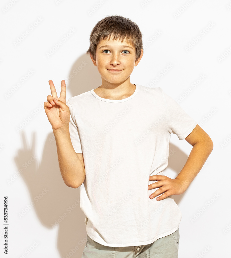 The boy shows a sign of peace to the camera and smiles. The boy shows a sign of peace to the camera and smiles.