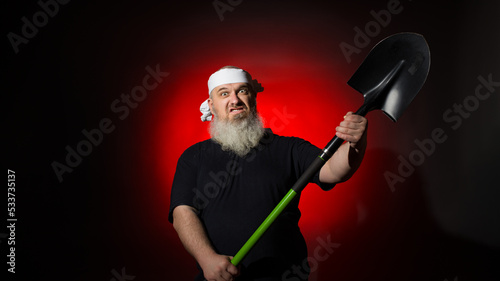 aggressive man with a beard brandishing a shovel on a red background