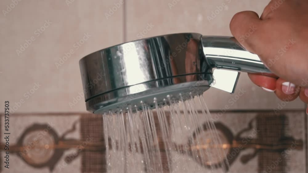 Stockvideo Woman's hand holds a shower in the bathroom from which water