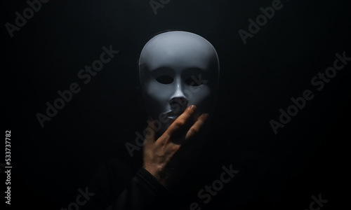 Fotografie Man in a hoodie takes off his mask.