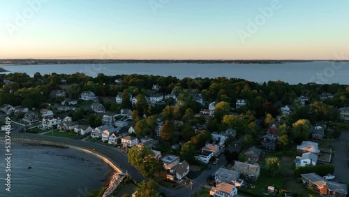 Aerial drone footage of Nahant, Massachusetts near Boston. Beautiful pink sky sunset on the Atlantic Ocean during summer. Waves on the rocky shoreline and Boston cityscape in the distance. photo