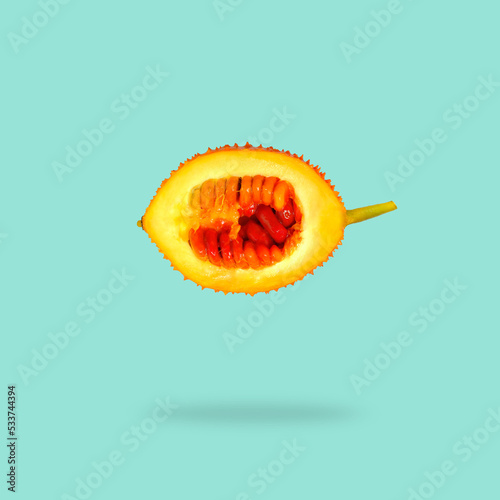 Gac fruit with cut in half falling in the air isolated on turquoise background.