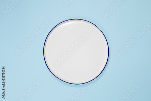 white plate in the center, top view, copy space. On a blue background