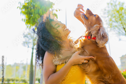 beautiful young woman with long dark curly hair with american cocker dog outdoors