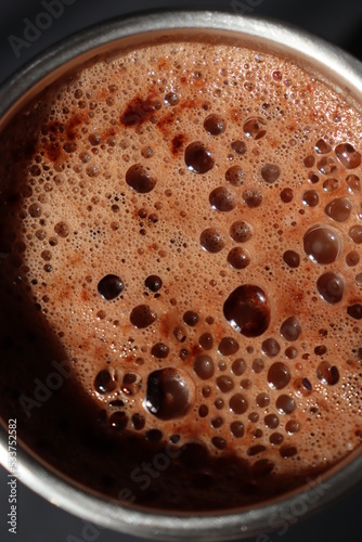 a thermo cup of cappuccino coffee on a black background © Diana Kozii